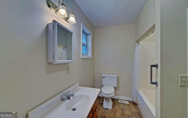 full bathroom featuring vanity, a textured ceiling, shower / bath combo with shower curtain, hardwood / wood-style flooring, and toilet