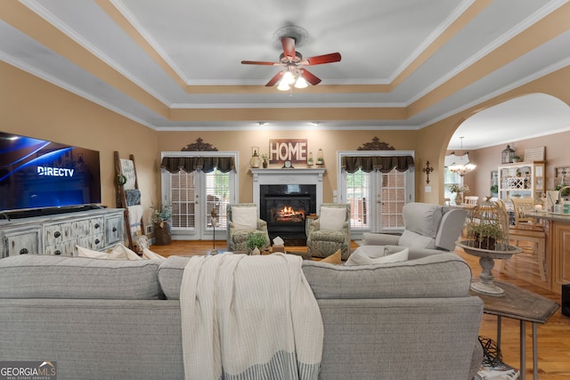 living room featuring french doors, light wood-type flooring, crown molding, and ceiling fan