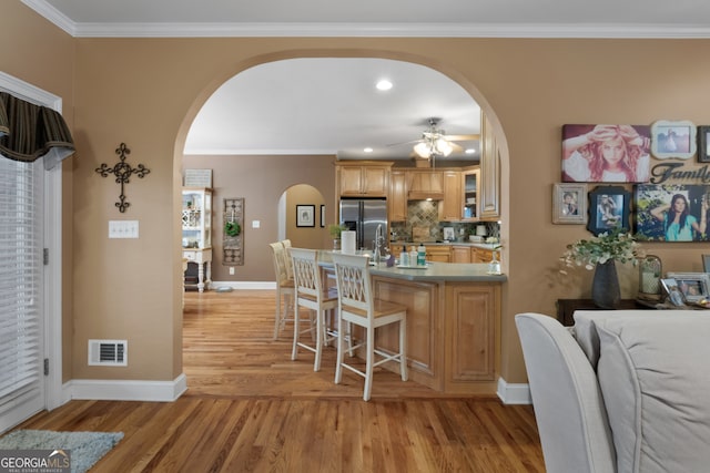 kitchen with ceiling fan, tasteful backsplash, stainless steel refrigerator with ice dispenser, light brown cabinetry, and light hardwood / wood-style floors