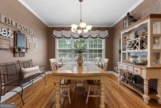 dining space with crown molding, an inviting chandelier, and light hardwood / wood-style flooring