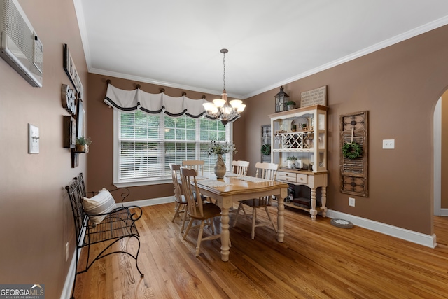 dining area featuring crown molding, light hardwood / wood-style floors, and an inviting chandelier