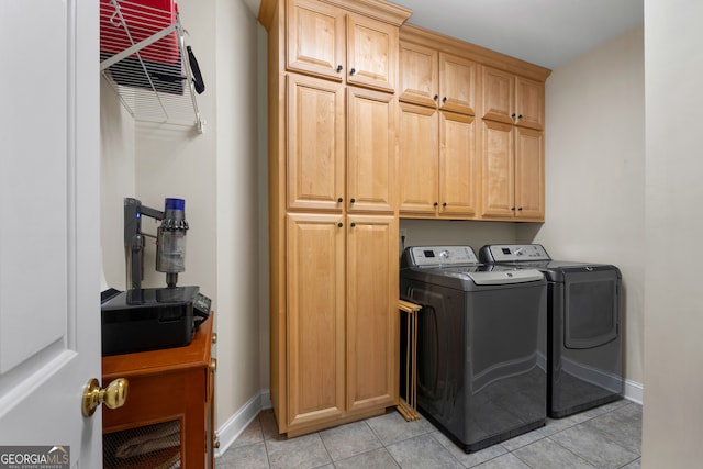 laundry area featuring cabinets, light tile patterned floors, and washing machine and dryer