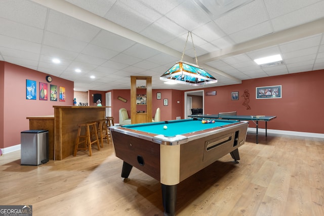 game room with a paneled ceiling, billiards, light hardwood / wood-style flooring, and indoor bar