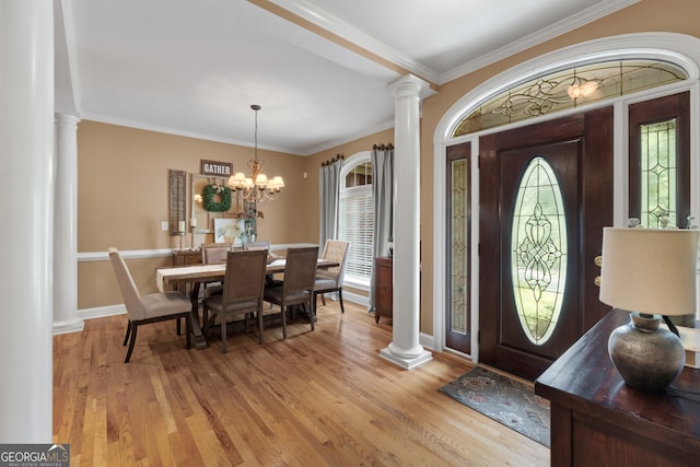 entryway featuring ornamental molding, an inviting chandelier, light wood-type flooring, and ornate columns