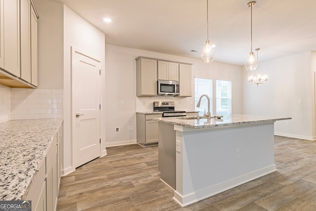 kitchen with light hardwood / wood-style flooring, gray cabinetry, appliances with stainless steel finishes, and backsplash