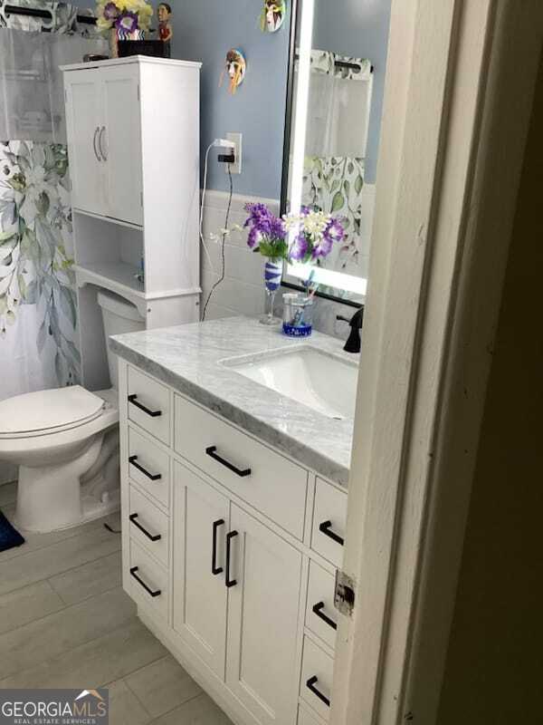 bathroom with walk in shower, vanity, toilet, and tile patterned floors