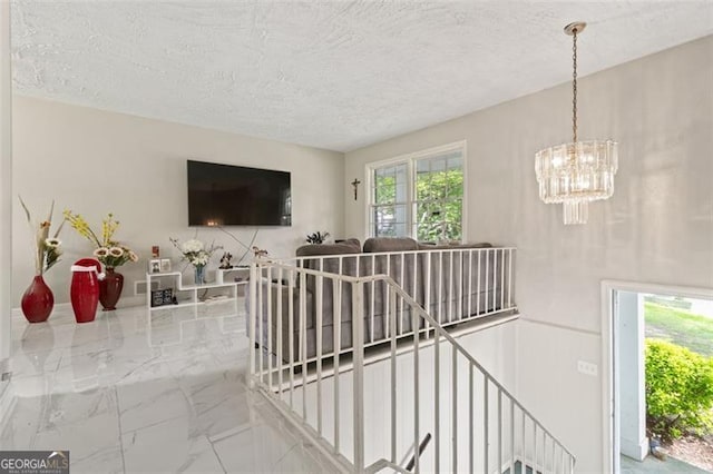 staircase with an inviting chandelier and a textured ceiling