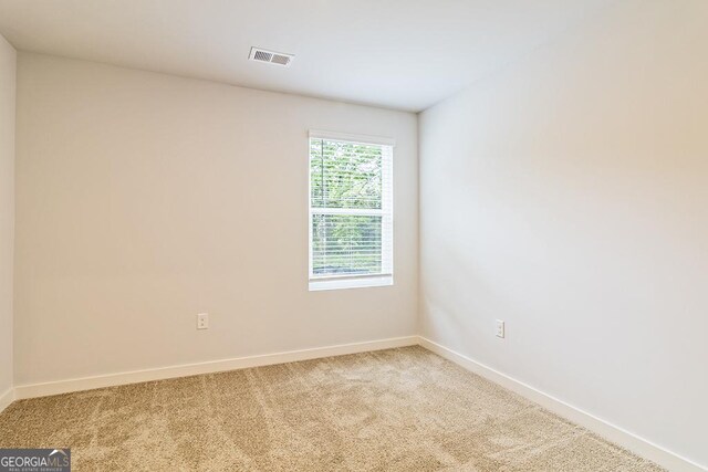 empty room with light carpet, visible vents, and baseboards