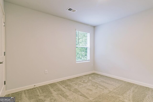 spare room featuring carpet, visible vents, and baseboards