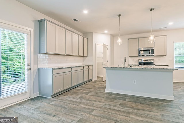 kitchen featuring visible vents, gray cabinetry, appliances with stainless steel finishes, a sink, and wood finished floors