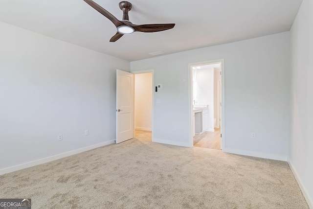 unfurnished bedroom featuring light colored carpet, connected bathroom, baseboards, and ceiling fan