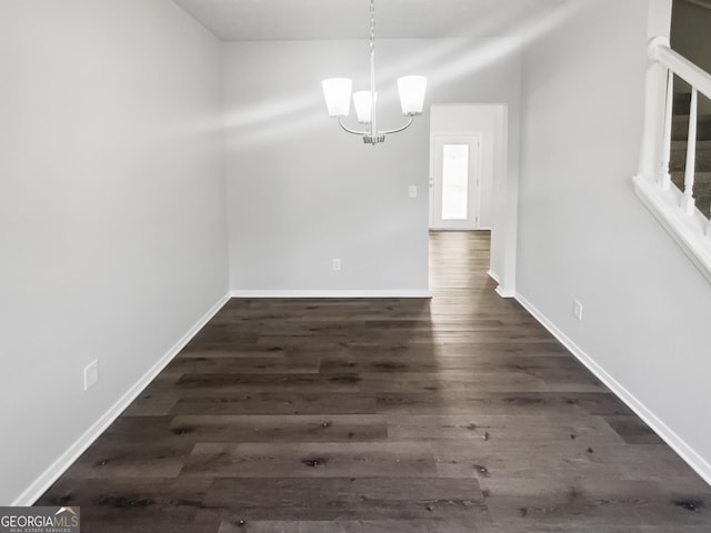 unfurnished dining area with a chandelier, baseboards, wood finished floors, and stairs