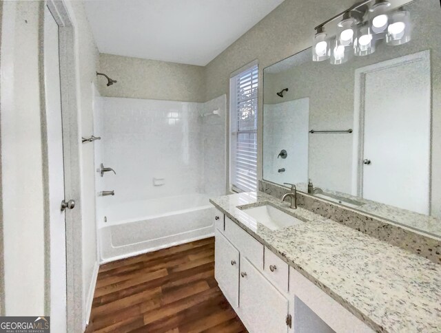 bathroom featuring wood-type flooring, tiled shower / bath, and vanity