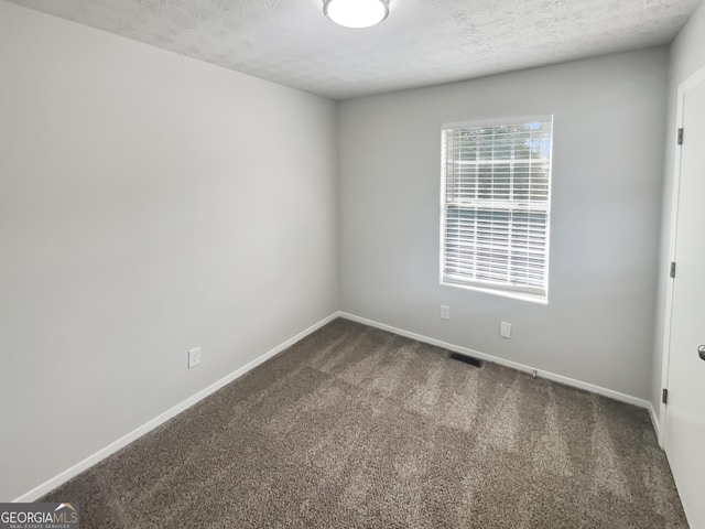 empty room with dark carpet, a textured ceiling, and baseboards