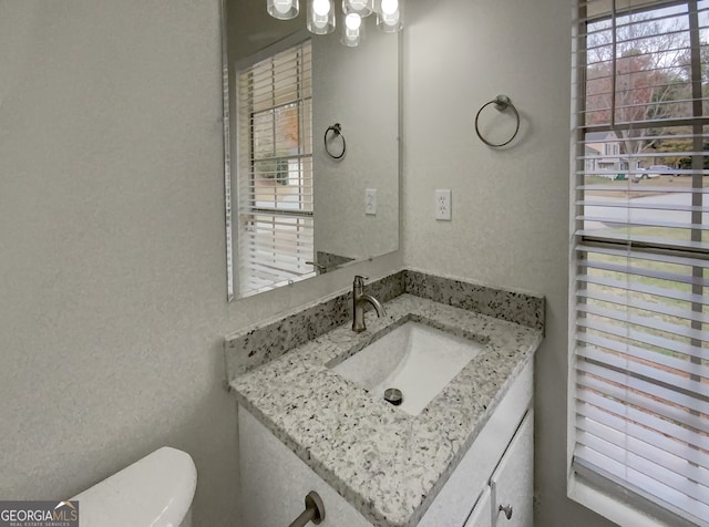 bathroom with vanity, toilet, and a healthy amount of sunlight