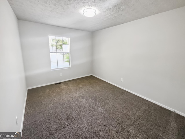 empty room with dark carpet, baseboards, and a textured ceiling