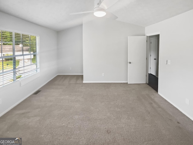 carpeted empty room with a ceiling fan, baseboards, and vaulted ceiling