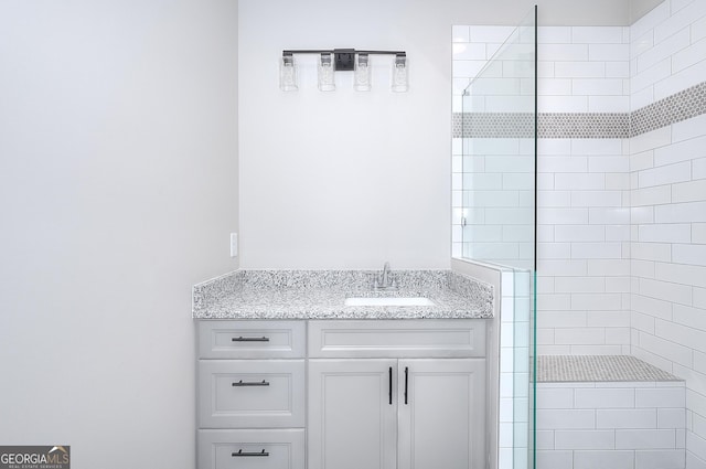 bathroom featuring a tile shower and vanity