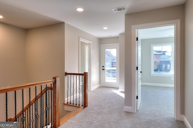 hall featuring light colored carpet and a healthy amount of sunlight