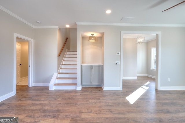 interior space featuring wood-type flooring, a notable chandelier, and ornamental molding