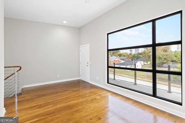 unfurnished room featuring wood-type flooring and a healthy amount of sunlight