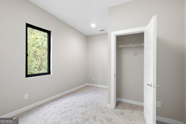 unfurnished bedroom with a closet and light colored carpet