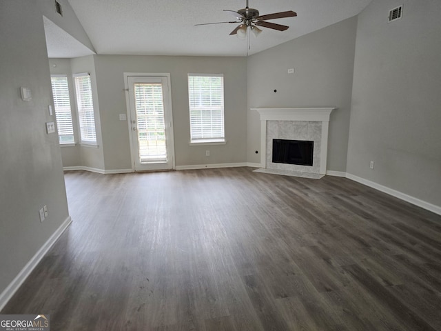 unfurnished living room featuring vaulted ceiling, dark hardwood / wood-style flooring, a textured ceiling, ceiling fan, and a premium fireplace