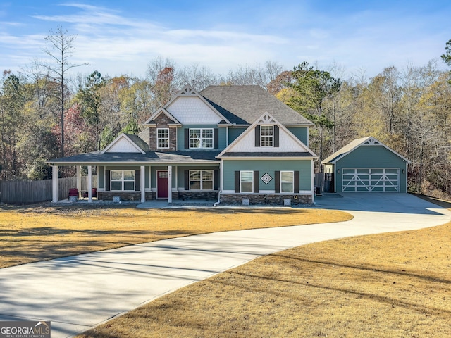 craftsman-style house with a porch, a garage, a front lawn, and an outdoor structure