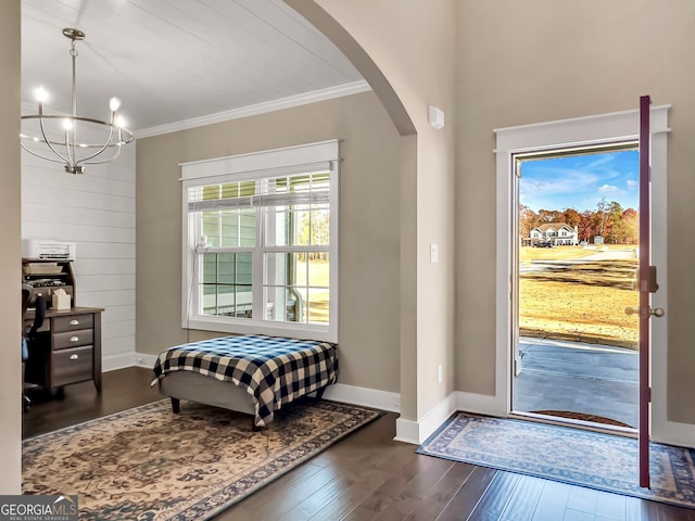 entrance foyer featuring a notable chandelier, plenty of natural light, dark hardwood / wood-style floors, and ornamental molding