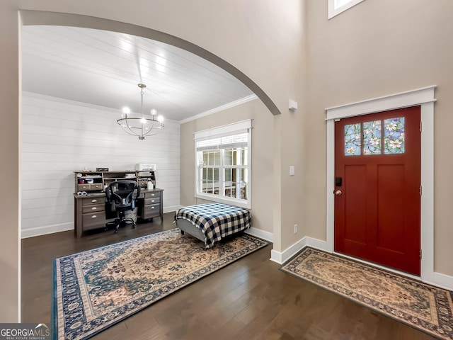 foyer entrance with dark hardwood / wood-style floors, an inviting chandelier, plenty of natural light, and crown molding