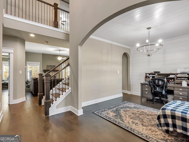 office featuring dark wood-type flooring, wooden ceiling, crown molding, wood walls, and ceiling fan with notable chandelier