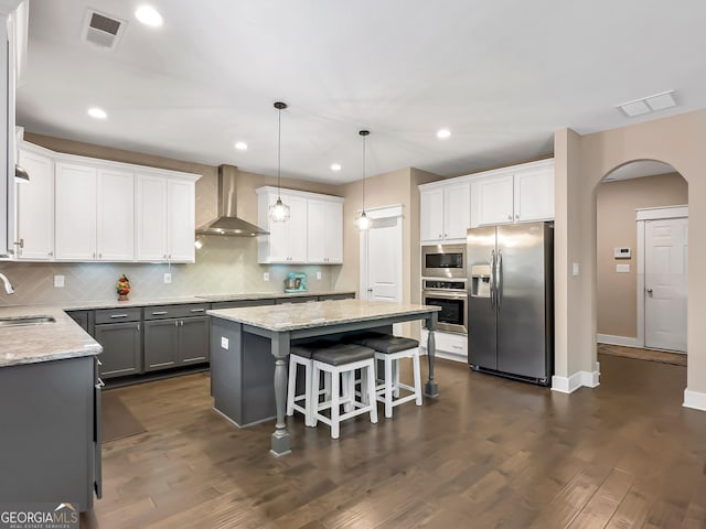 kitchen with wall chimney exhaust hood, stainless steel appliances, dark hardwood / wood-style floors, gray cabinets, and white cabinets