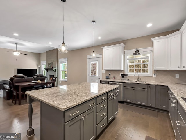 kitchen featuring white cabinets, a healthy amount of sunlight, a kitchen island, and hanging light fixtures