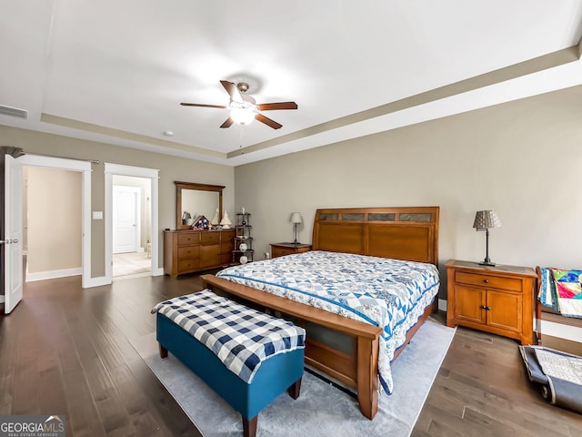 bedroom featuring a tray ceiling, ceiling fan, and dark wood-type flooring