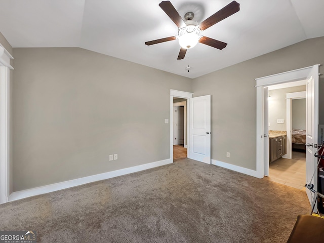 unfurnished bedroom featuring ceiling fan, ensuite bathroom, lofted ceiling, and light carpet