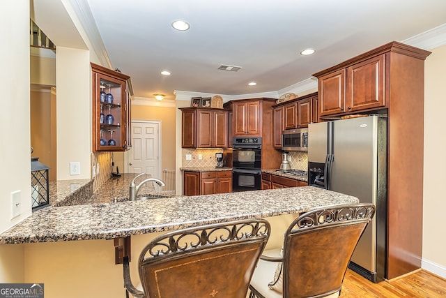 kitchen with a kitchen breakfast bar, light hardwood / wood-style floors, kitchen peninsula, stainless steel appliances, and crown molding