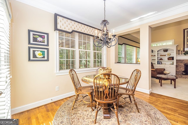 dining space with a fireplace, ornamental molding, an inviting chandelier, and plenty of natural light