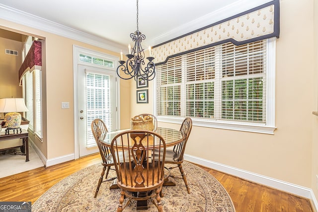 dining area featuring an inviting chandelier, ornamental molding, and hardwood / wood-style flooring