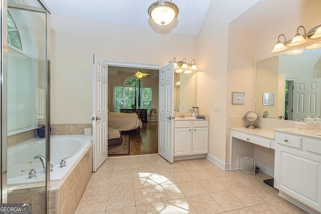 bathroom featuring tiled tub, vanity, vaulted ceiling, and tile patterned flooring