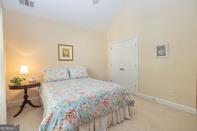 bedroom with a closet, vaulted ceiling, ceiling fan, and light colored carpet