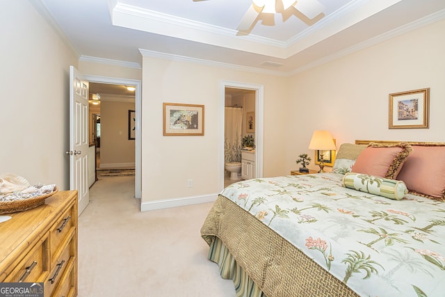 carpeted bedroom with ceiling fan, a tray ceiling, crown molding, and ensuite bathroom