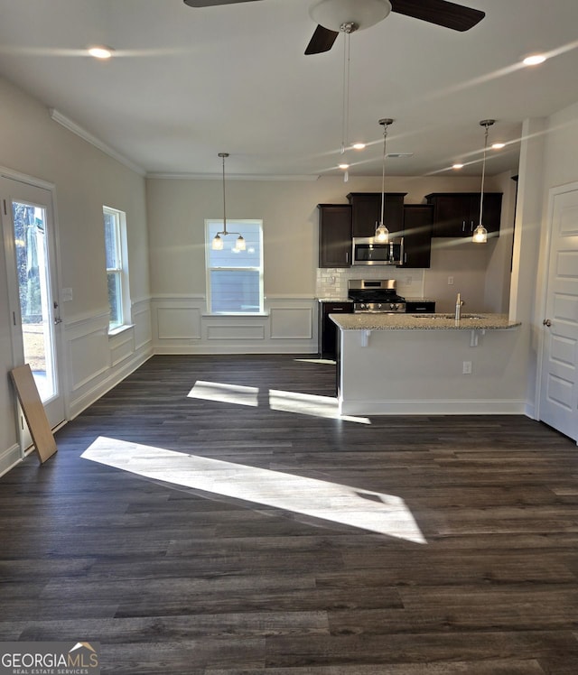 kitchen with light stone counters, hanging light fixtures, appliances with stainless steel finishes, and a breakfast bar area