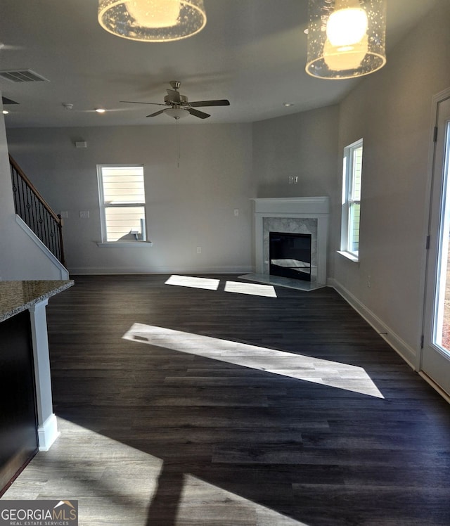 unfurnished living room featuring dark wood-style flooring, a fireplace, visible vents, baseboards, and stairs