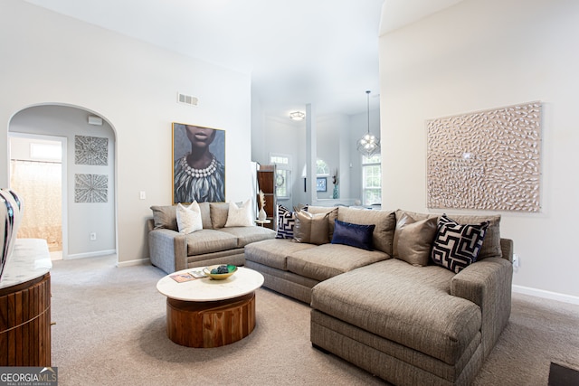 carpeted living room with a notable chandelier and a towering ceiling