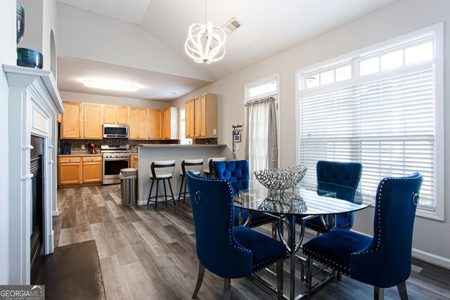 dining space with lofted ceiling, dark hardwood / wood-style floors, and a notable chandelier