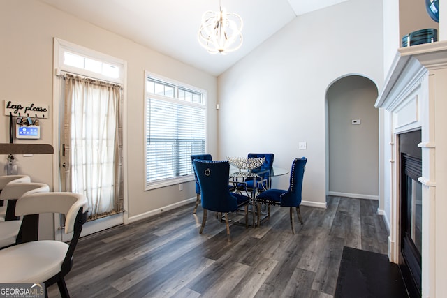 dining area featuring a notable chandelier, lofted ceiling, dark wood-type flooring, and a wealth of natural light