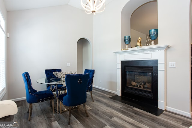 dining area featuring wood-type flooring, an inviting chandelier, and lofted ceiling