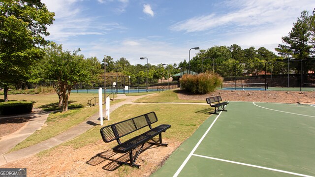 view of property's community with a lawn and tennis court