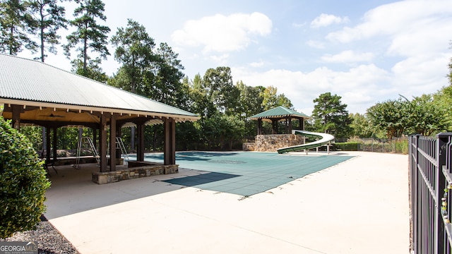 view of swimming pool featuring ceiling fan, a gazebo, a water slide, and a patio area