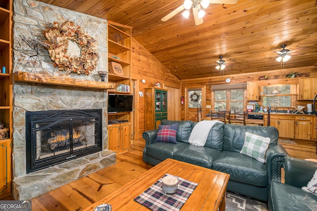 living room with vaulted ceiling, a fireplace, wood walls, wood-type flooring, and ceiling fan